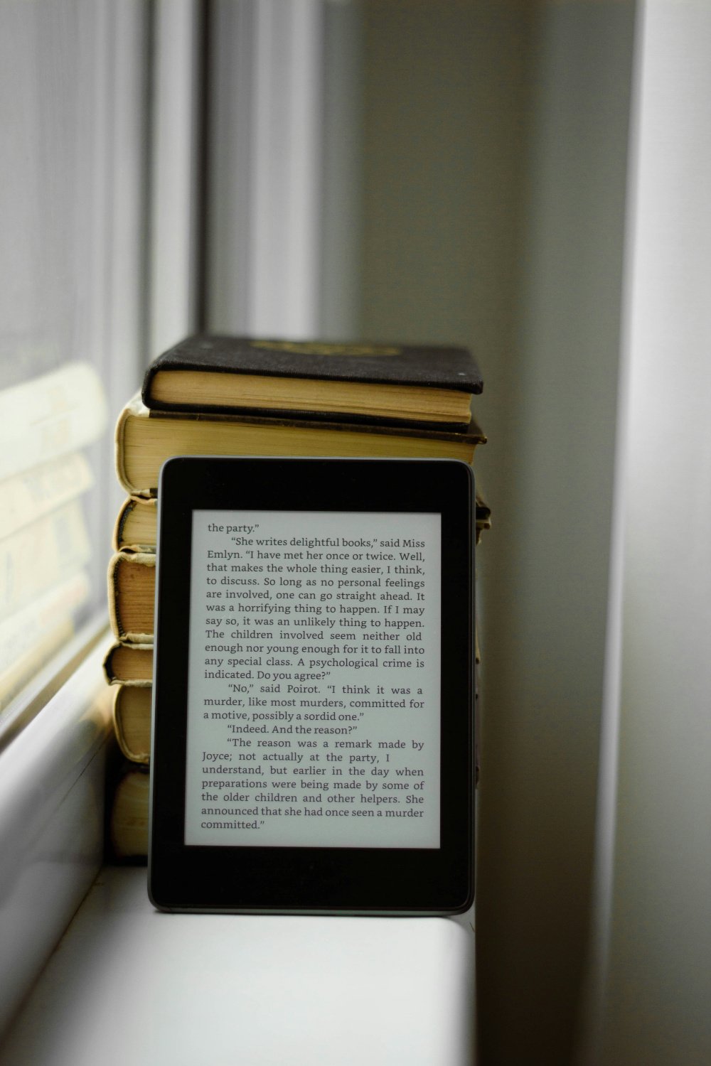 An e-reader resting on a stack of books